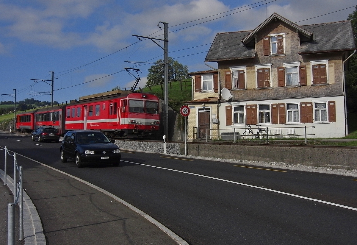 Bei einem Gro�teil der Strecke zwischen Appenzell und St. Gallen liegen die Gleise der Appenzeller Bahn parallel zur Stra�e. Wie auch hier in Hirschberg, wo S11 2166 nach St. Gallen gerade die gleichlautende Haltestelle verlassen hat (21.09.2013).