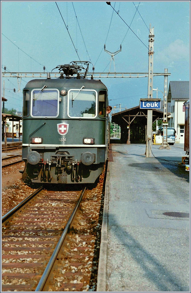 Die Re 4/4 11334, noch in grün, aber bereits ab Fabrik mit eckigen Lampen geliefert, wartet im alten Bahnhof von Leuk auf den Abfahrtsbefehl, um mit ihrem Schnellzug nach Brig abzufahren.

im Juli 1995