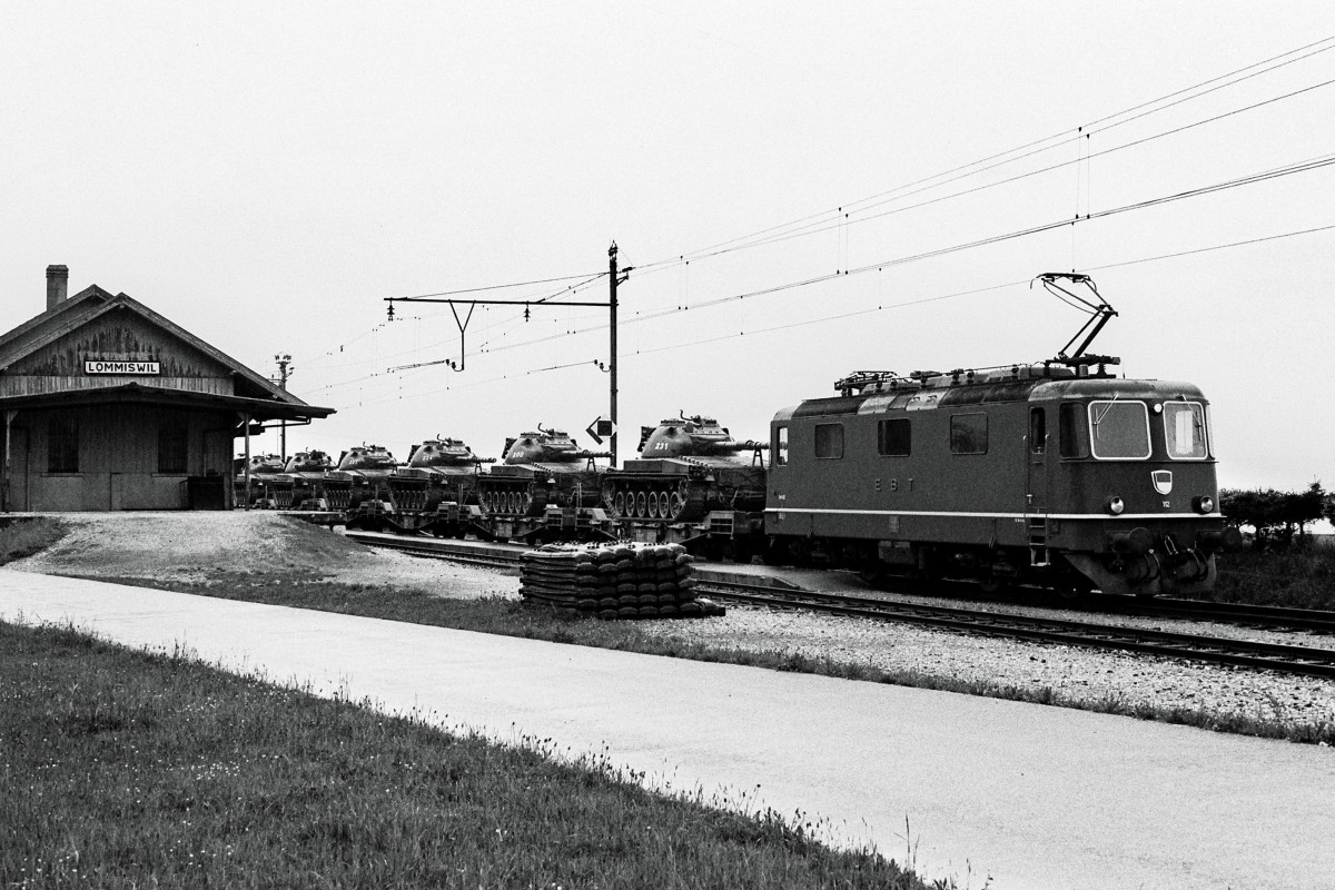 RM/SMB: Verschiebung des Pz Bat 13 Burgdorf - Bure via Solothurn-Moutier. Im Jahre 1980 wartete die Re 4/4 112 (1969)  SOLOTHURN  mit einem mit Pz 61 beladenen Kurzpanzerzug in Lommiswil die Zugskreuzung mit einem Planzug aus Moutier ab. Anfangs der 90er-Jahre gab es noch einen Armeebestand von 150 Pz 61. Inzwischen wurden sie ausrangiert. Die Re 4/4 112 hingegen leistet noch immer wertvolle Dienste bei Crossrail AG im allt�glichen Nord- S�dverkehr.
Foto: Walter Ruetsch  