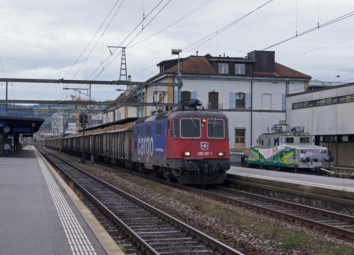SBB/TRAVYS/YStC: Die Re 420 307 von SBB CARGO trifft bei der Durchfahrt Yverdon les Bains kurz auf die abgestellte YStC Ge 4/4 21. Nebst R�benwagen f�r die Zuckerfabrik Frauenfeld werden auch noch geschlossene G�terwagen mitgef�hrt. Die Zufallsaufnahme bei sehr schlechter Witterung ist am 16. Oktober 2014 entstanden.
Foto: Walter Ruetsch 