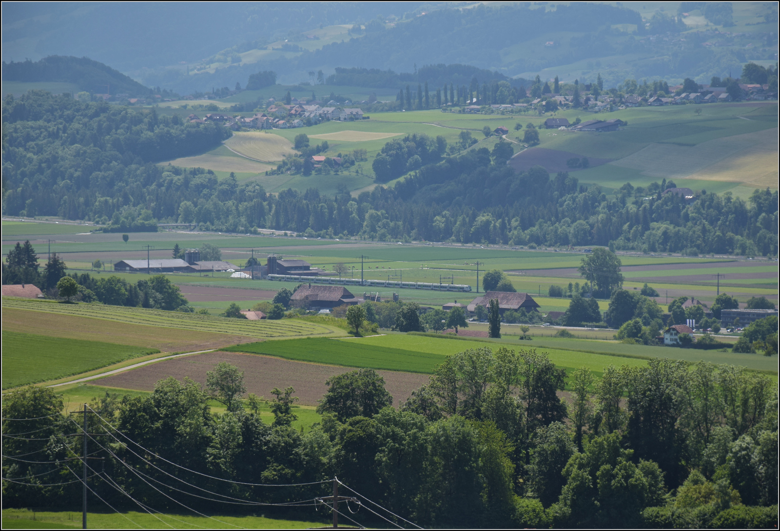 Der Blick darf auch mal in die Ferne schweifen, im Aaretal f�hrt bei M�nsingen eine Doppeltraktion Mika RABe 528 in Regionalzugversion vorbei. Mai 2025.
