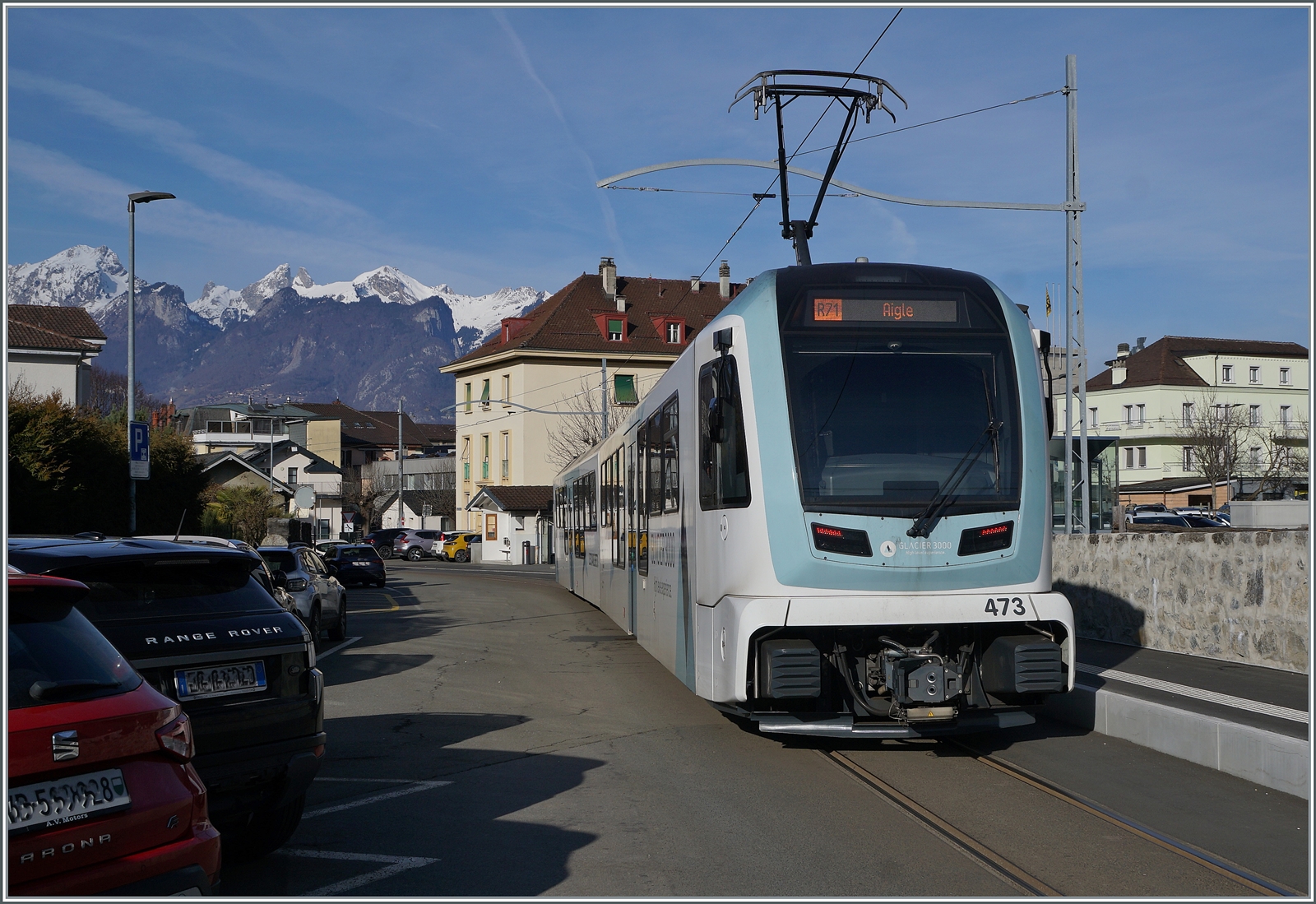 Der TPC ASD ABe 4/8 473 ist als R71 von Les Diablerets nach Aigle unterwegs und hält kurz in Aigle Place du Marché. Die Haltestelle ist nun mit einem Bahnsteig versehen worden und befindet sich gut 50 Meter nördlicher der  alten  Haltestelle. Zudem wurden wie bereits erwähnt neue, den alten sehr gut nachempfundene Fahrleitungsmasten aufgestellt. 9. Februar 2026