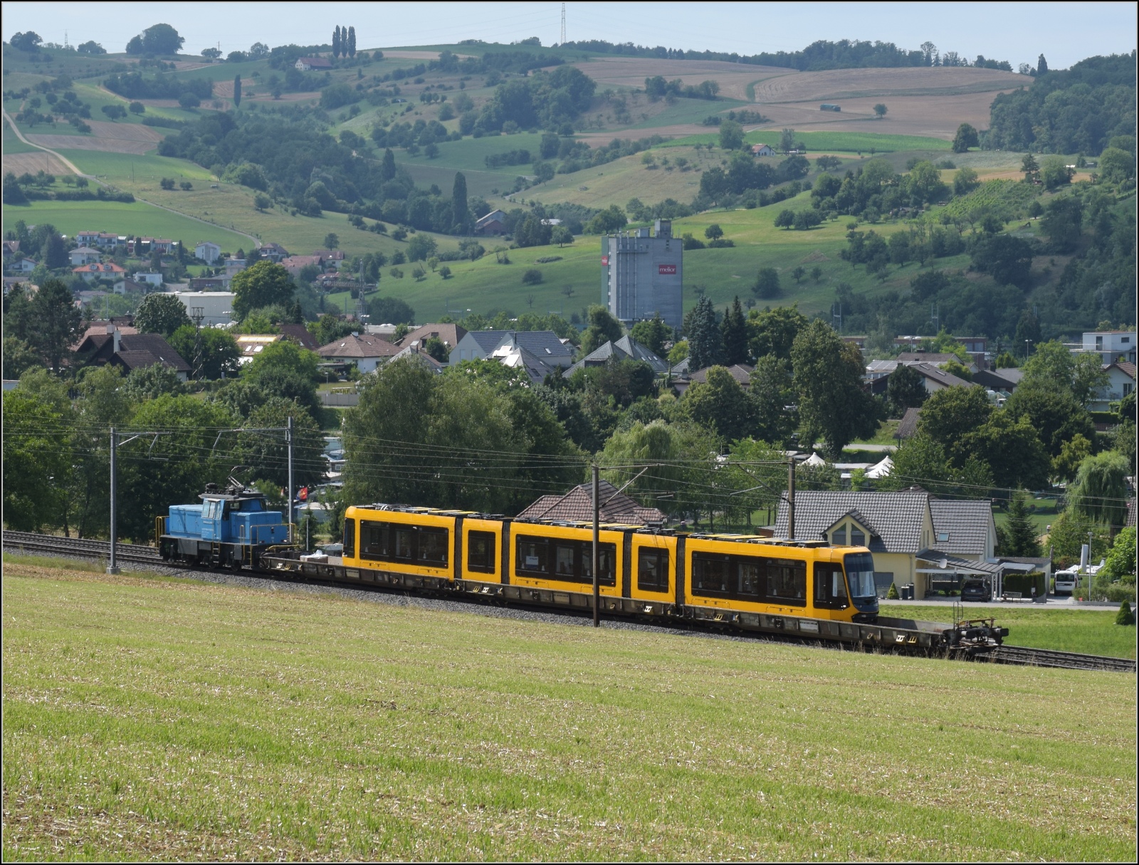 Die Stadler-Werkslok Eem 936 131 liefert eine neue TINA-Strassenbahn nach Darmstadt aus. Auf dem Weg in Frick, Juli 2023.

TINA steht für: Total Integrierter Niederflur Antrieb. Damit wird in Darmstadt die neueste Technologie von Stadler erstmals in Betrieb genommen. Die Daten sind hier im Produktdatenblatt zusammengestellt: http://www.stadlerrail.com/media/pdf/theag22_de.pdf